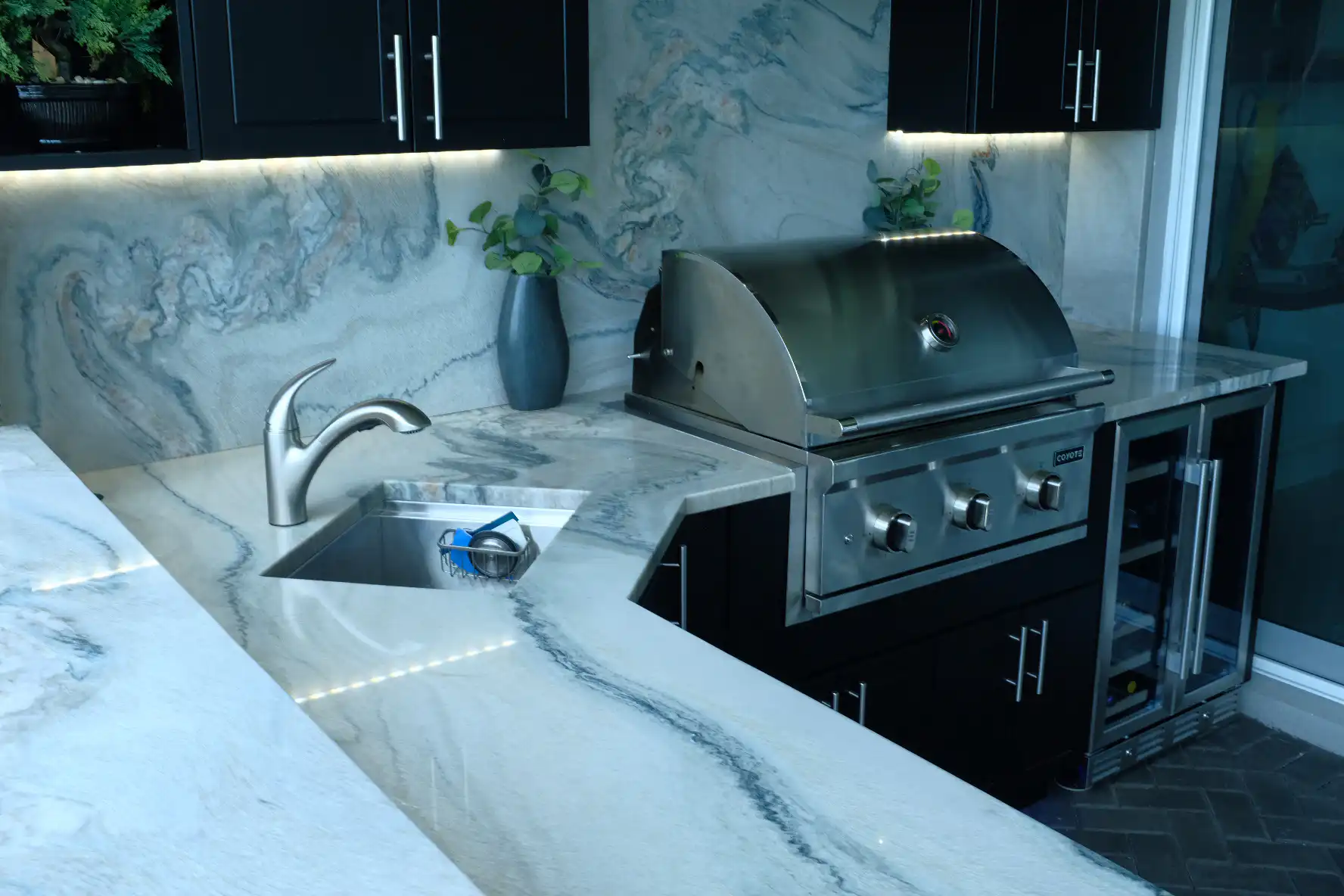 Close-up of Macaubas quartzite countertops and backsplash with Coyote C-Series grill and Werever black cabinets in Boynton Beach outdoor kitchen