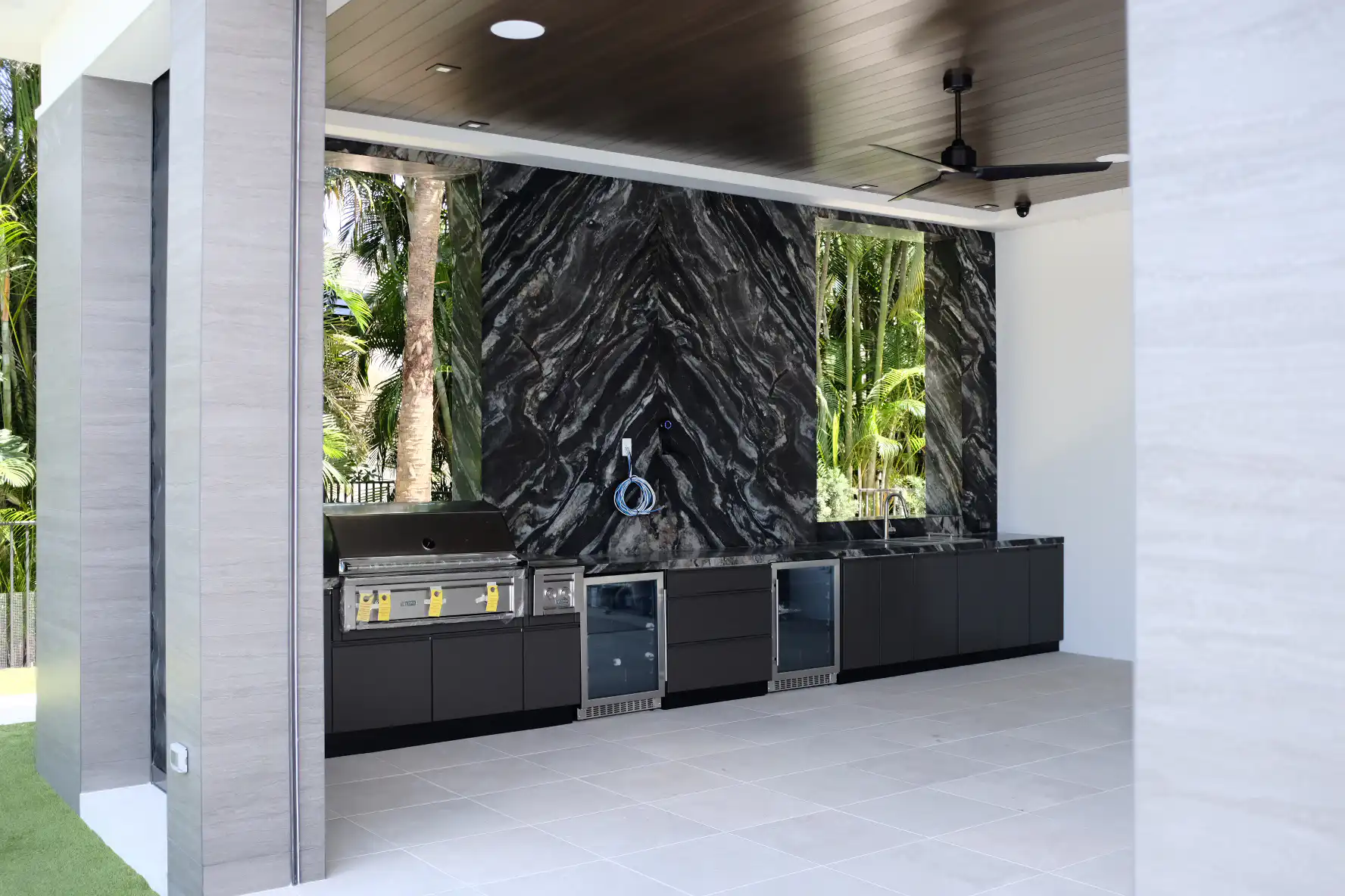Luxury outdoor kitchen in Addison Reserve Delray Beach featuring Belvedere quartzite backsplash with book-matched veining, Lynx Professional 42-inch infrared grill, Azure glass-front refrigerator, and Danver metallic bronze cabinets